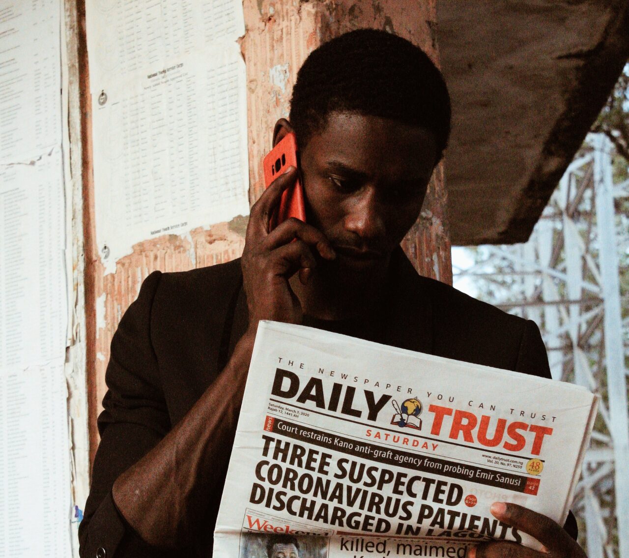 Black man speaking on phone while reading newspaper